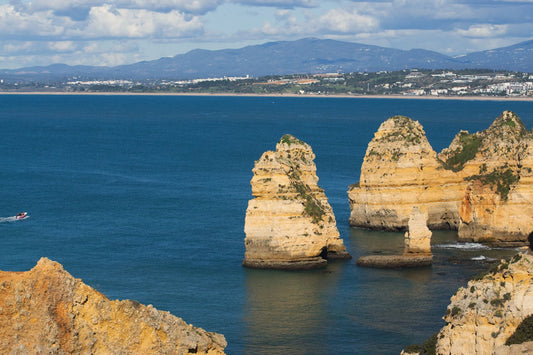 Best eSIM Portugal; scenic ocean view in Portugal showing rocky coastline with mountains in the background