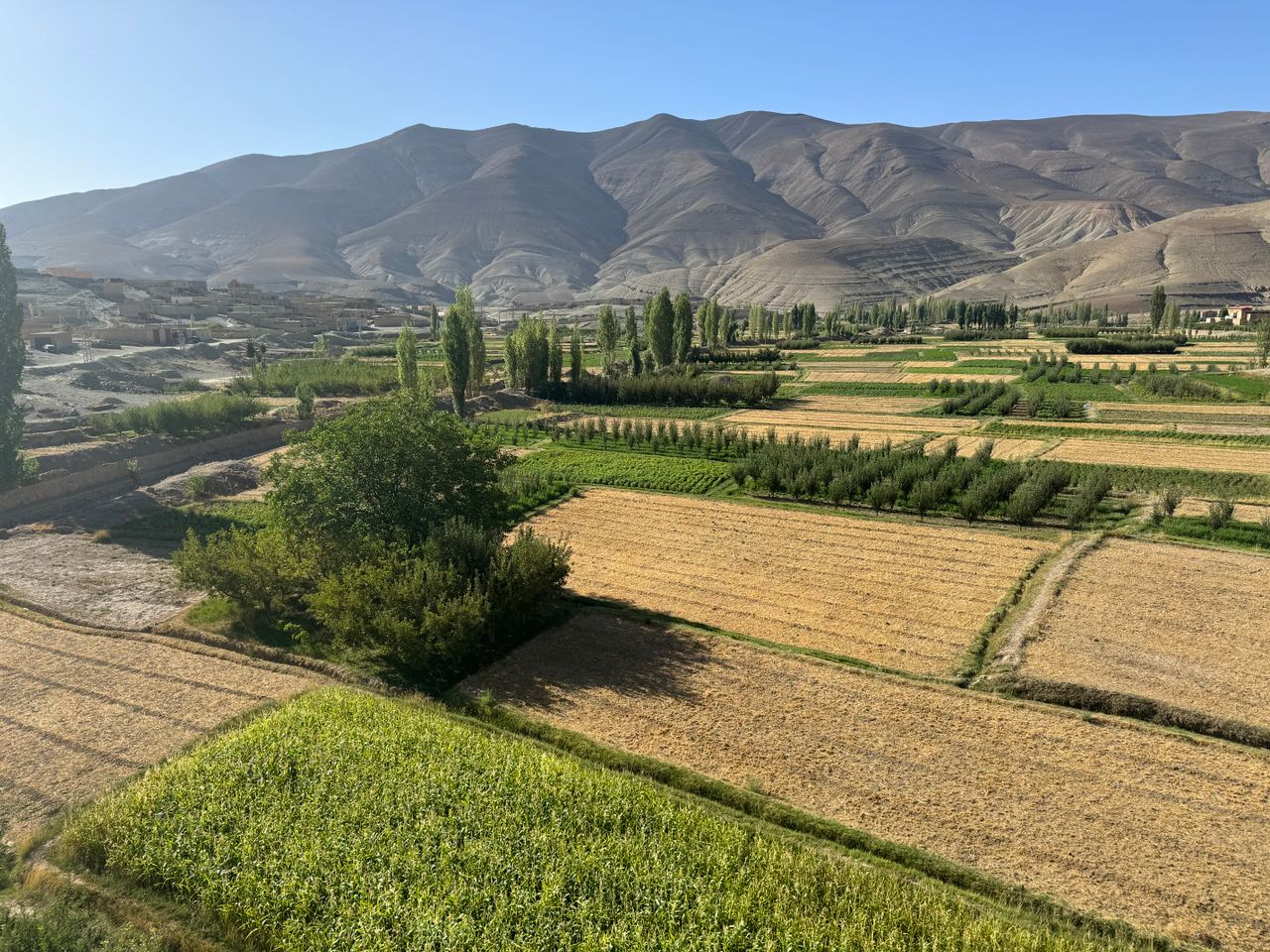 Best eSIM for Afghanistan; a scenic famring valley in Afghanistan with barren mountains in the background.
