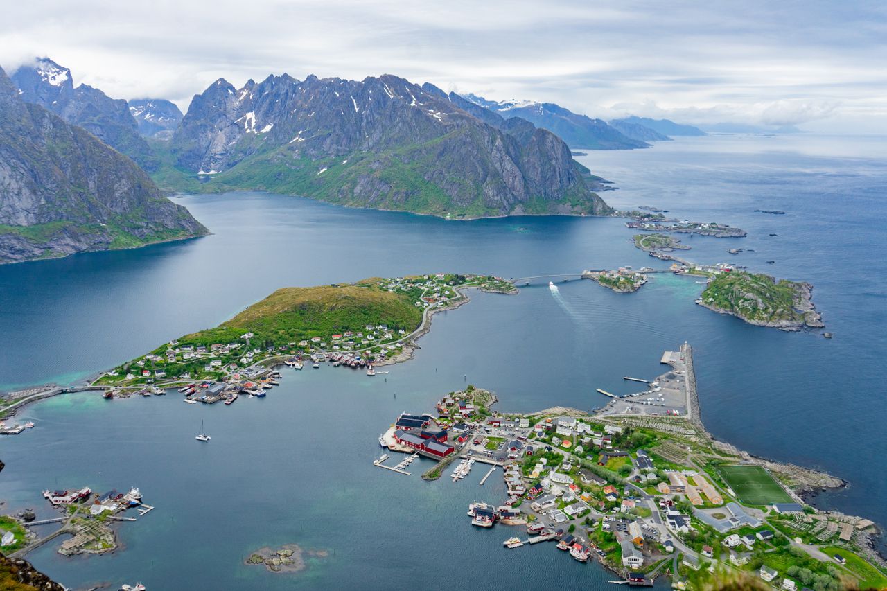 Best eSIM for Aland Islands; aerial view of a fjord landscape with steep rocky mountains, deep blue water, small green islands, and coastal villages with boats and docks in the Aland Islands.