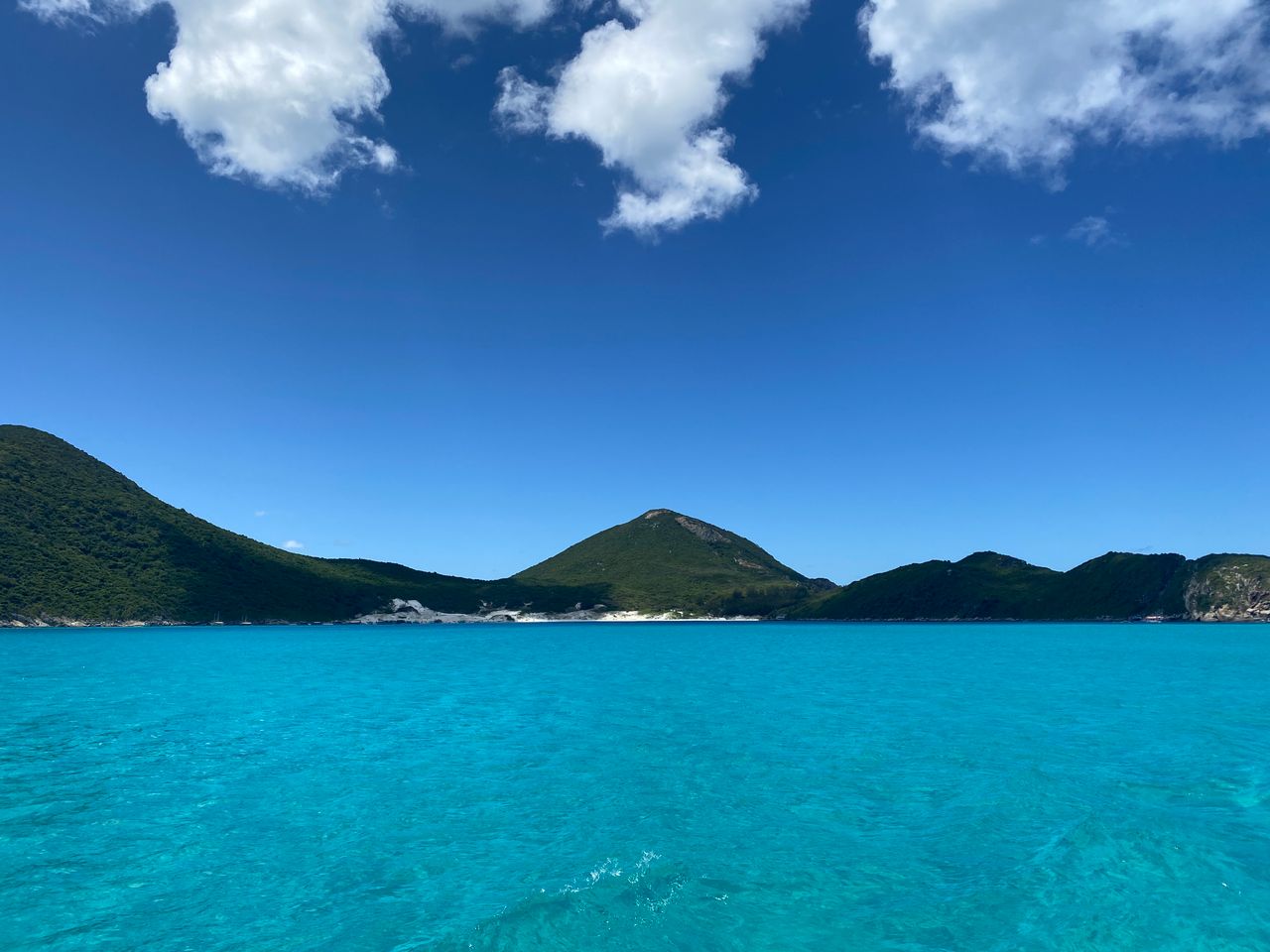 Best eSIM for British Virgin Islands travel; a view of turquoise water under a deep blue sky with scattered white clouds in the BVI.