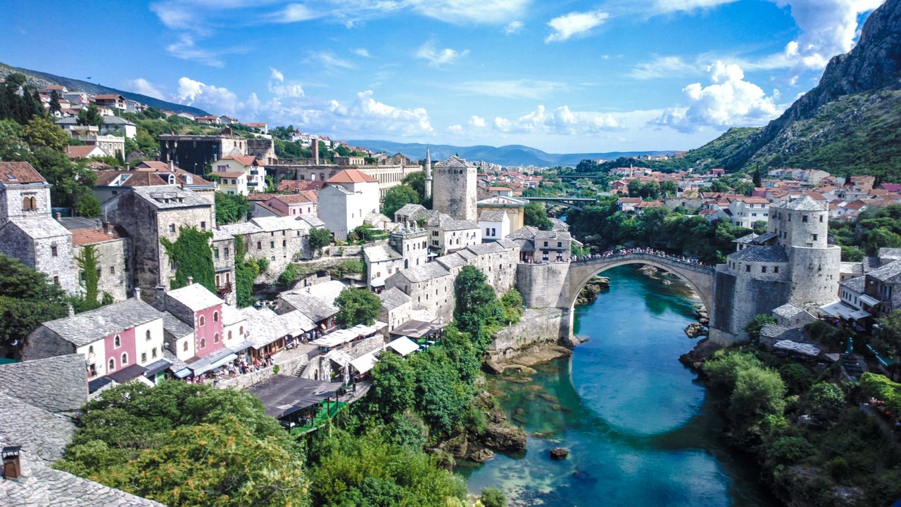 Balkans regional eSIM plans - photo of a historic Balkan town with a bridge over a river, surrounded by greenery and mountains.