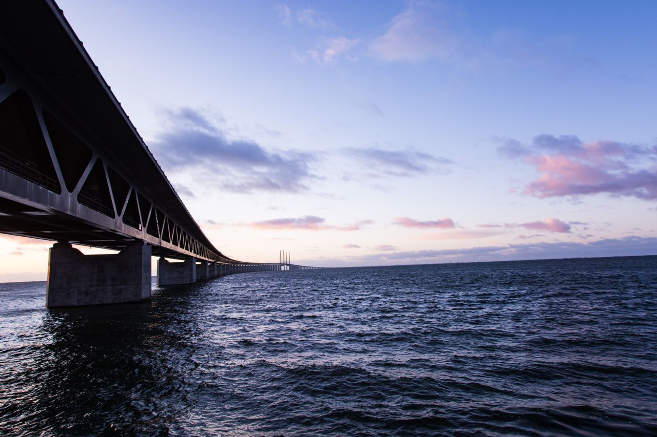 Best Denmark eSIM for travel - photo of a long bridge extending over dark blue water under a pastel sky in Denmark.