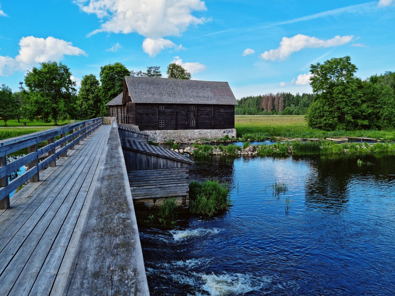 Best Estonia eSIM for travel - photo of a scenic pond and wooden bridge with barn in the background.