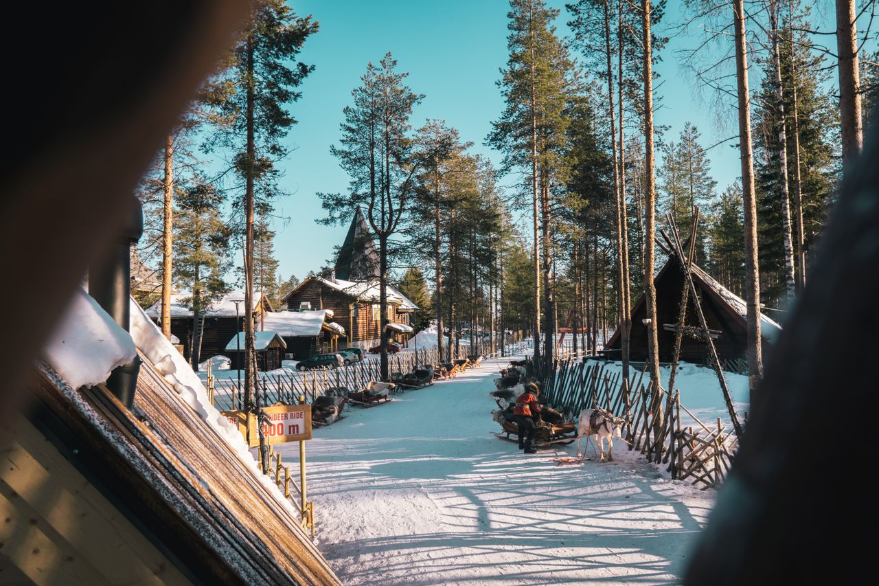Best eSIM Finland - photo of a snowy outdoor path lined with tall evergreen trees and rustic cabins in Finland.
