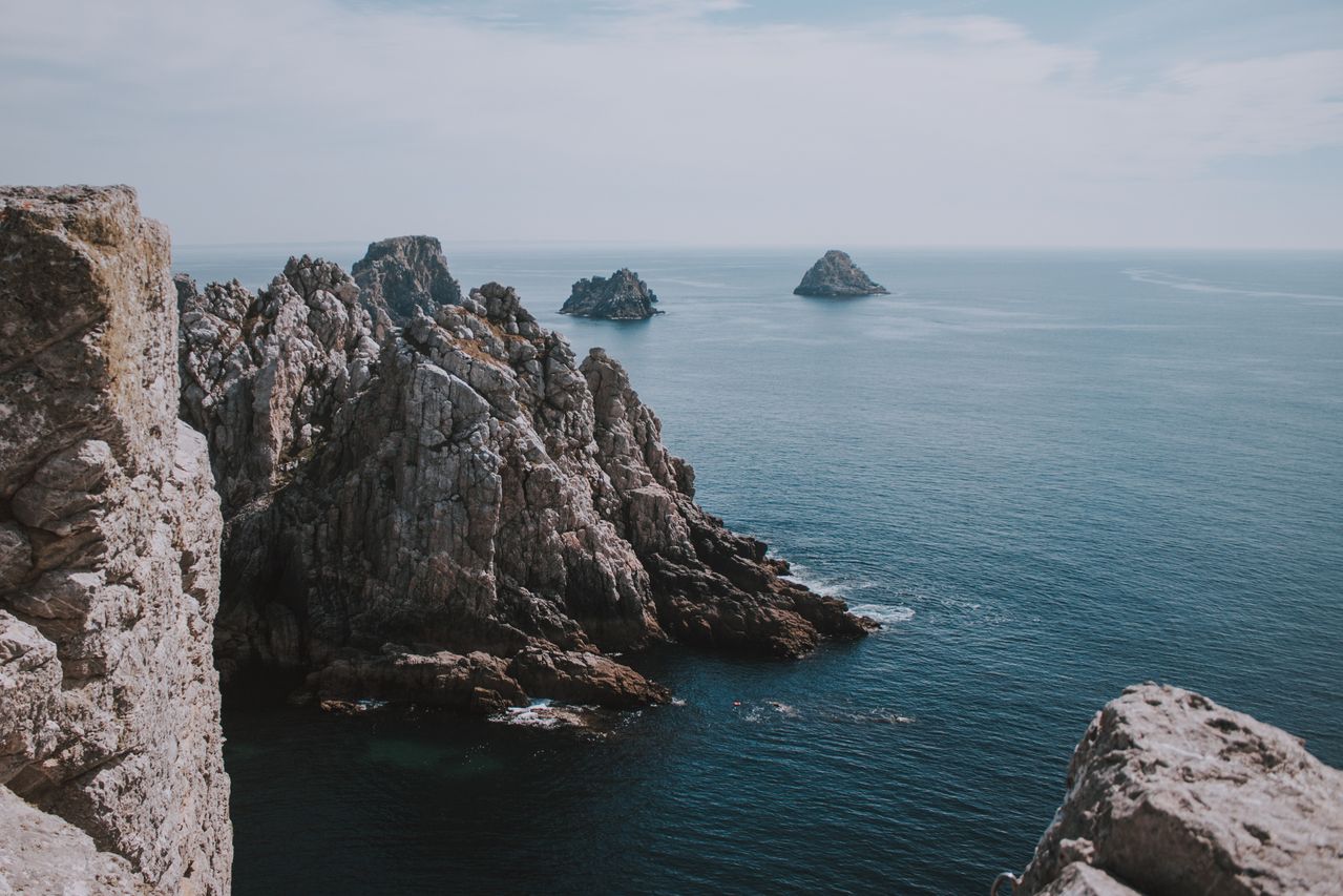 Best Guernsey eSIM for travel; a scenic coastal landscape with jagged rocky cliffs dropping into deep blue ocean water.