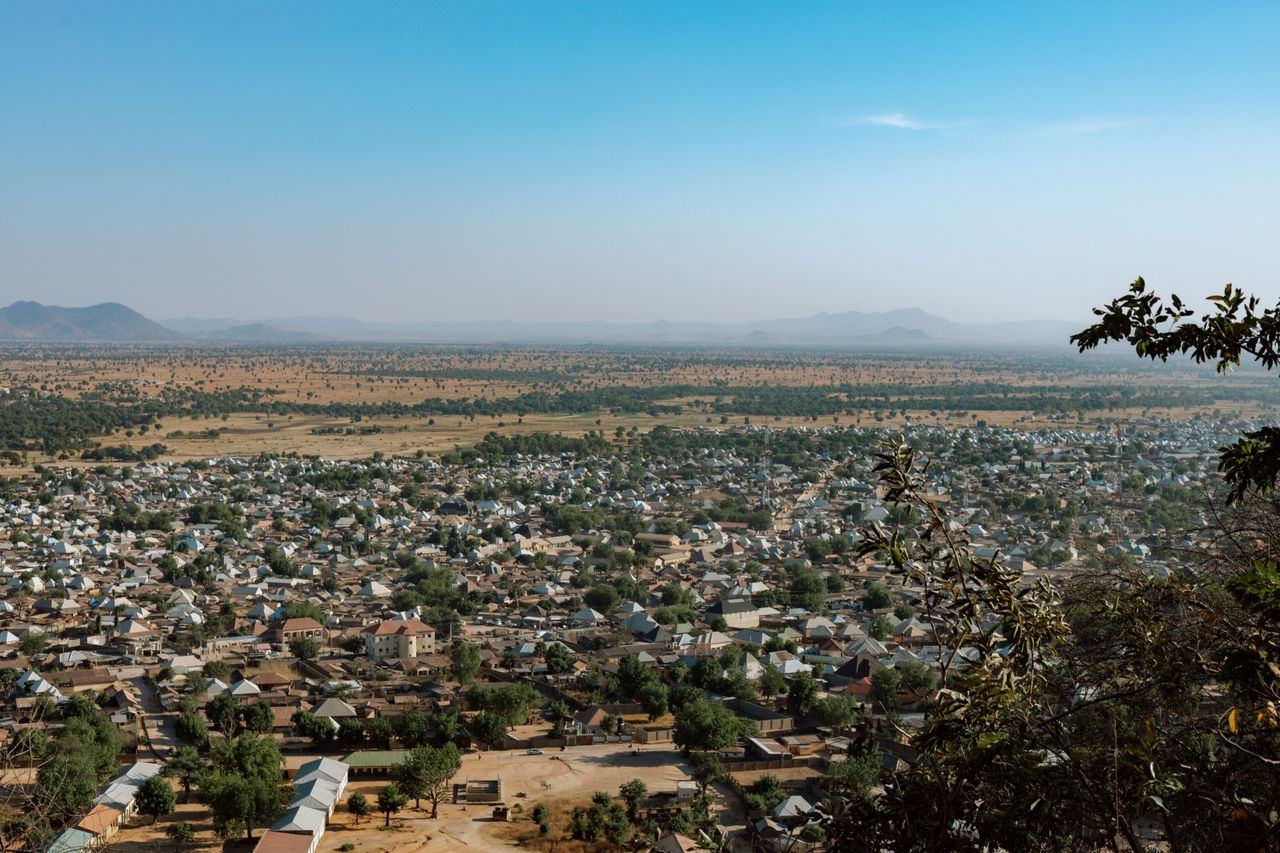 Best eSIM Guinea-Bissau; a wide scenic view of a town sprawling across a dry valley, with mountains in the distance under a clear blue sky.