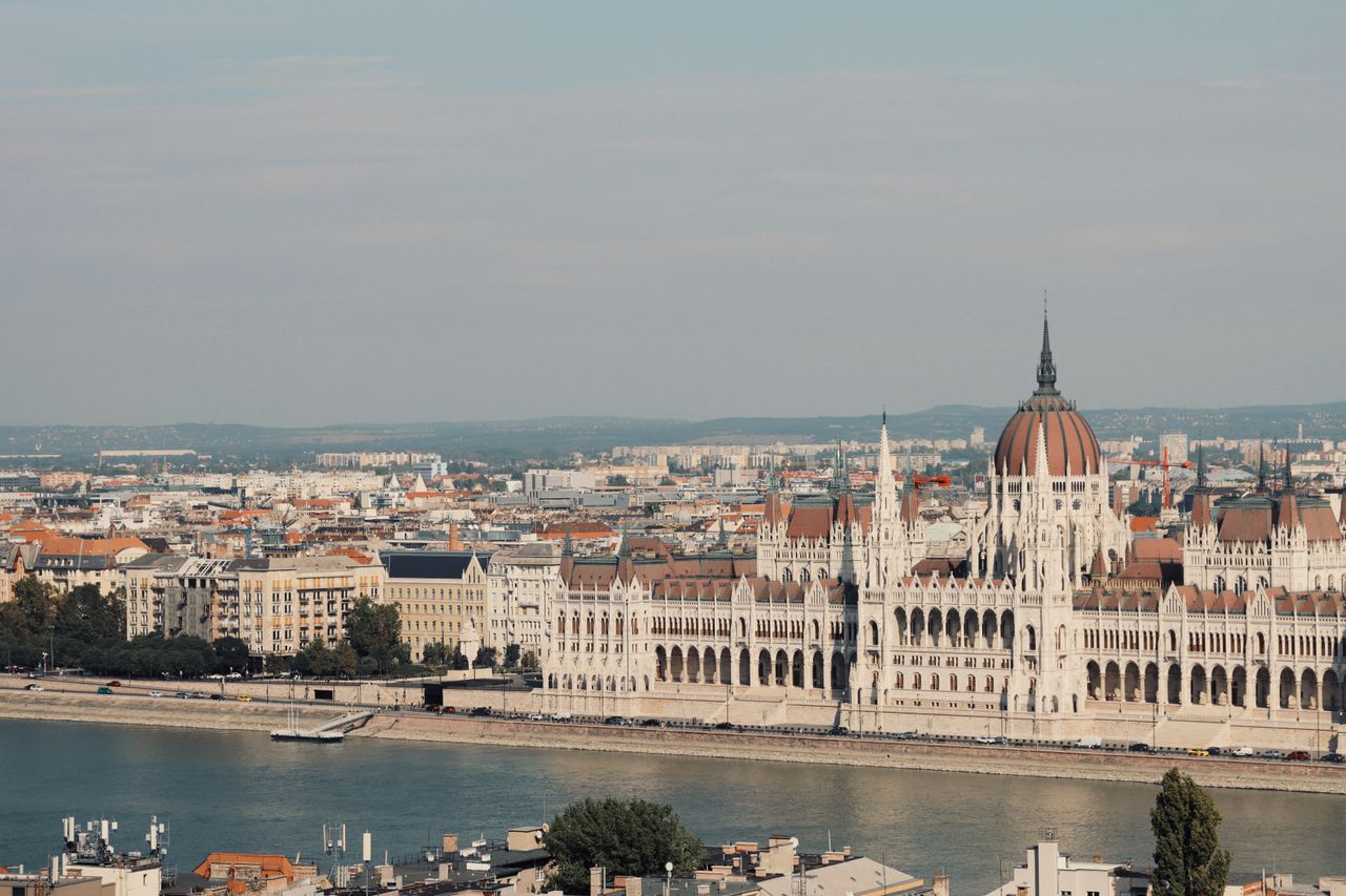 Best Hungary eSIM for travel; panoramic view of Budapest's Parliament building across the Danube river, with the city skyline stretching into the distance in Hungary.