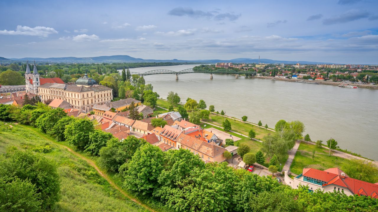 Best eSIM for Hungary - photo of a scenic aerial view of a town in Hungary beside a wide river, with a large historic building, red-roofed buildings.