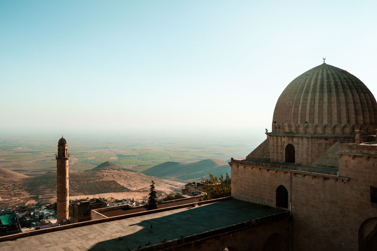 Best eSIM for Iraq; photo of a traditional domed brick building in Iraq overlooking a fertile valley.