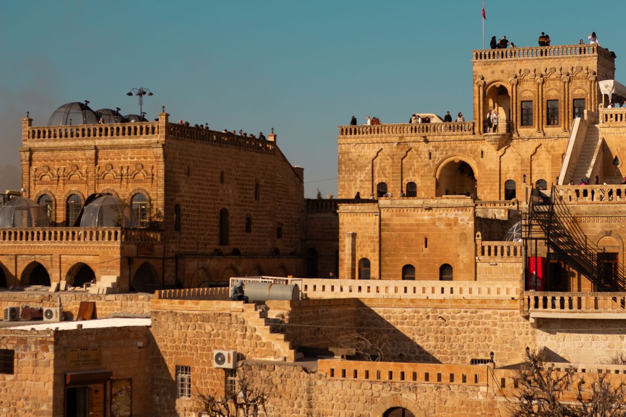 Best Iraq eSIM; sunlit stone palace and fortress in Iraq with arched windows, crenellated walls, and a clear blue sky in the background.