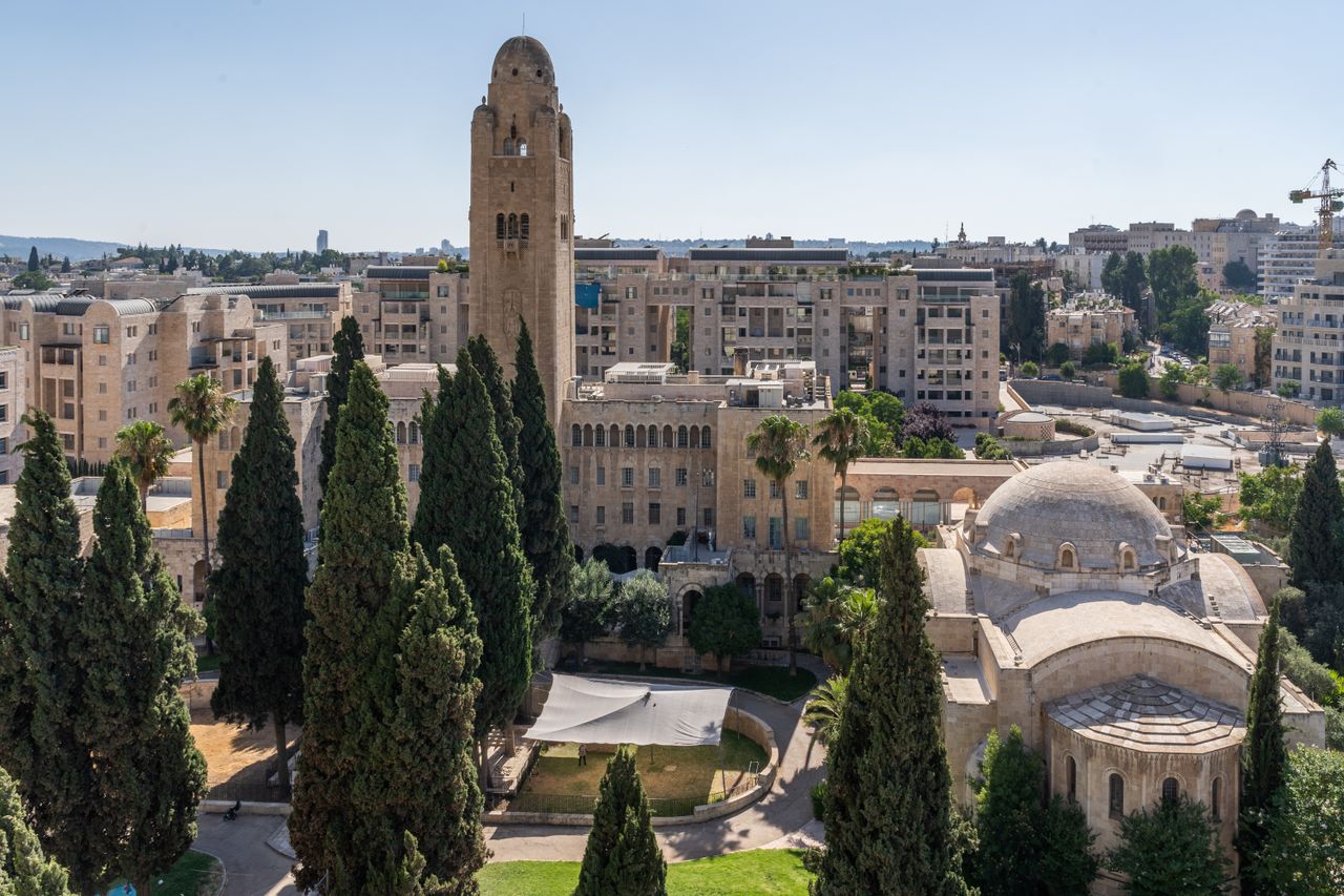 Best eSIM for Israel; aerial view of a historic cityscape in Israel with a tall stone tower, domed buildings, modern apartment buildings.
