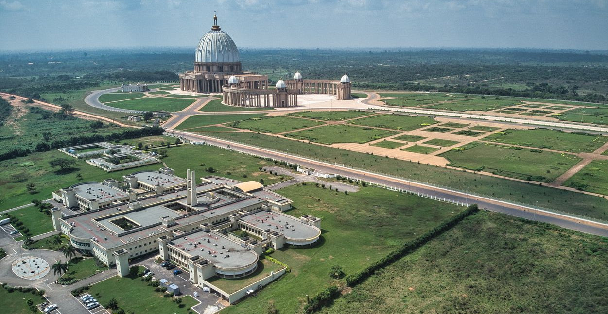 Best eSIM for Cote d'Ivoire; scenic view of a large green plain in Ivory Coast with modern and traditional buildings.