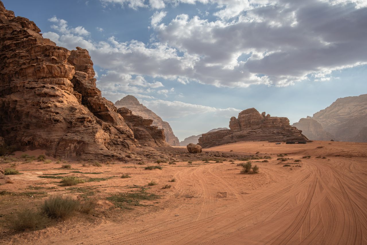 Best Jordan eSIM for travel; a scenic desert landscape in Jordanwith reddish sand dunes, rock formations, sparse shrubs.