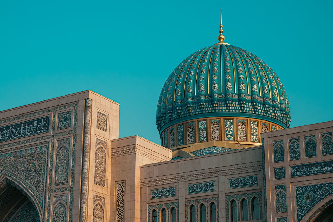 Best eSIM for Kazakhstan: a close-up architectural view of a large turquoise and gold domed mosque structure against a clear blue sky in Kazakhstan.