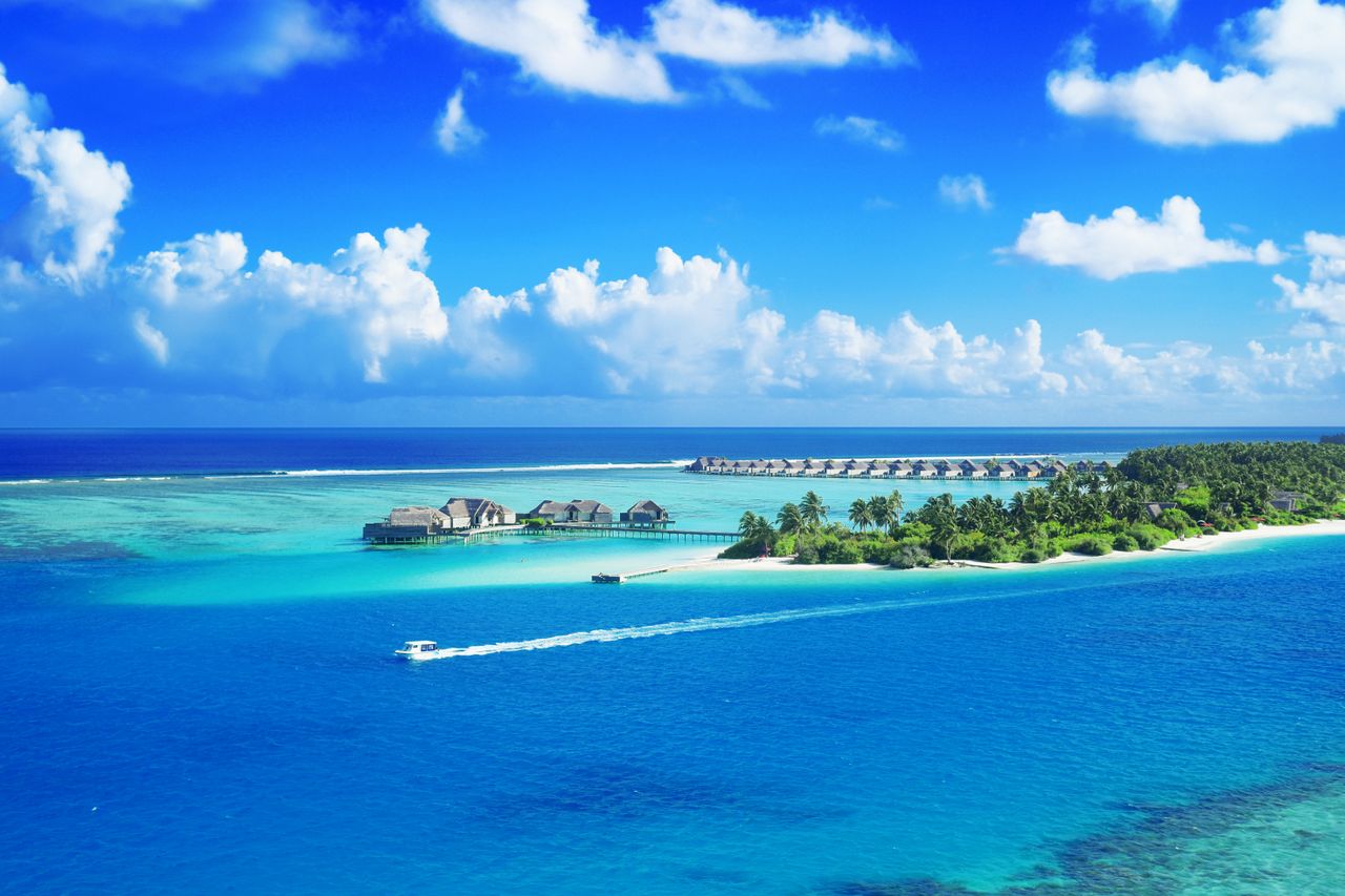 Best eSIM for the Maldives; a view of a tropical island in the Maldives with clear blue water and white clouds.