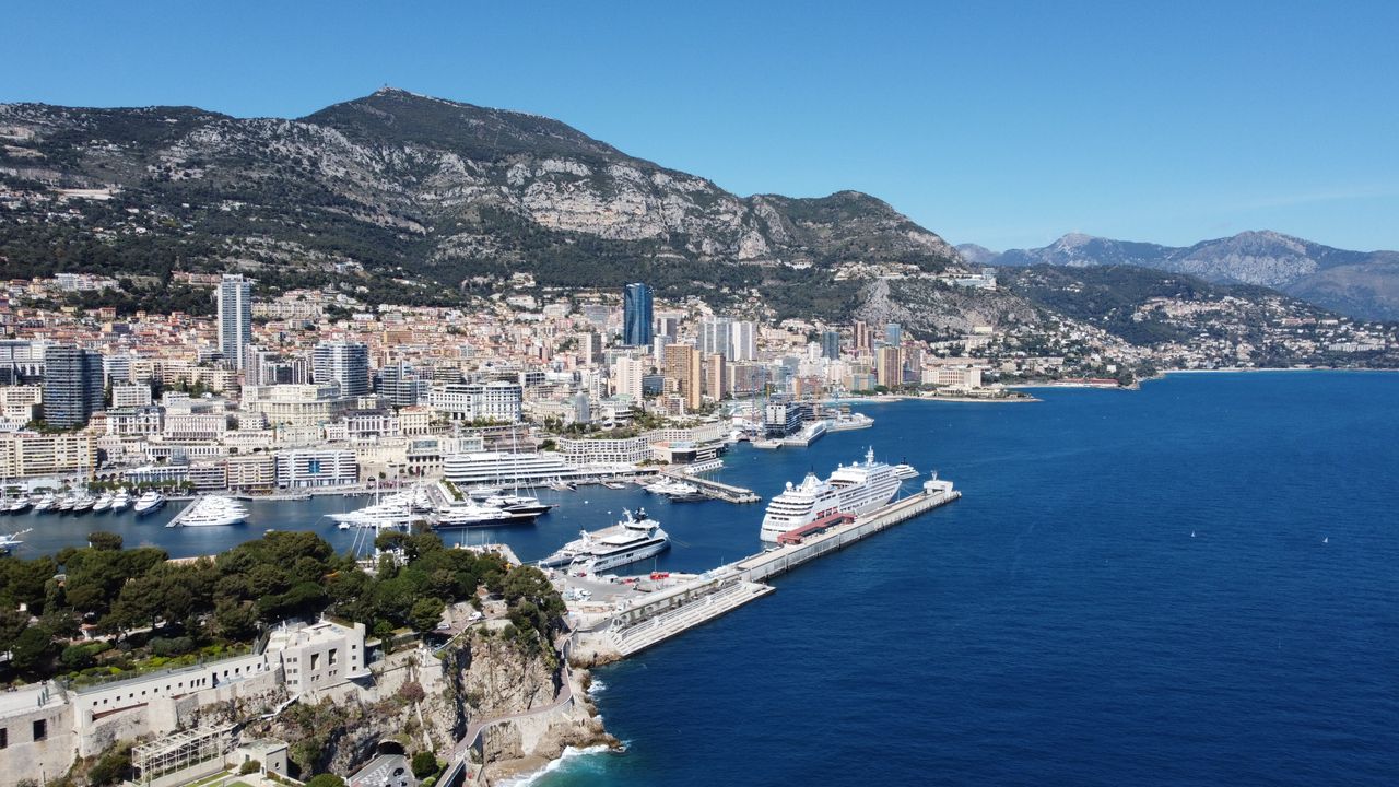 Best eSIM for Monaco; view of the Monaco harbour with mountains in the background and a blue bay with various boats moored.