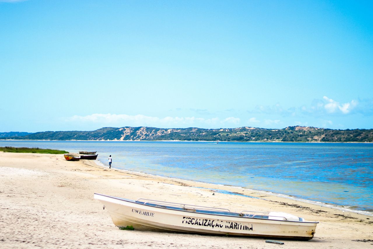 Best eSIM for Mozambique; a beach scene in Mozambique showing several small boats on the sand beside a blue body of water.