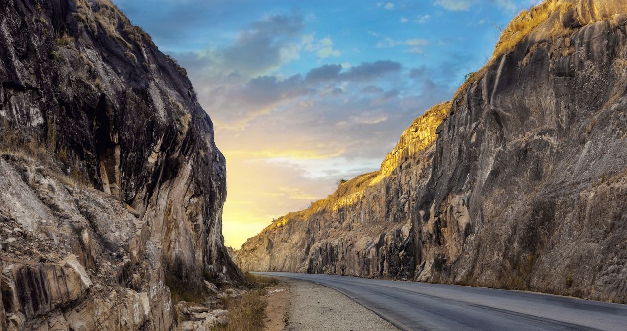 Best eSIM for Nigeria; a winding paved road running through a rocky canyon in Nigeria under a blue sky with warm golden light on the cliff faces.