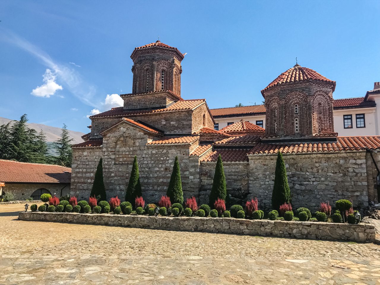 Best eSIM for North Macedonia travel; a scenic photograph of a historic stone monastery in North Macedonia with red-tiled domes and minarets under a clear blue sky.