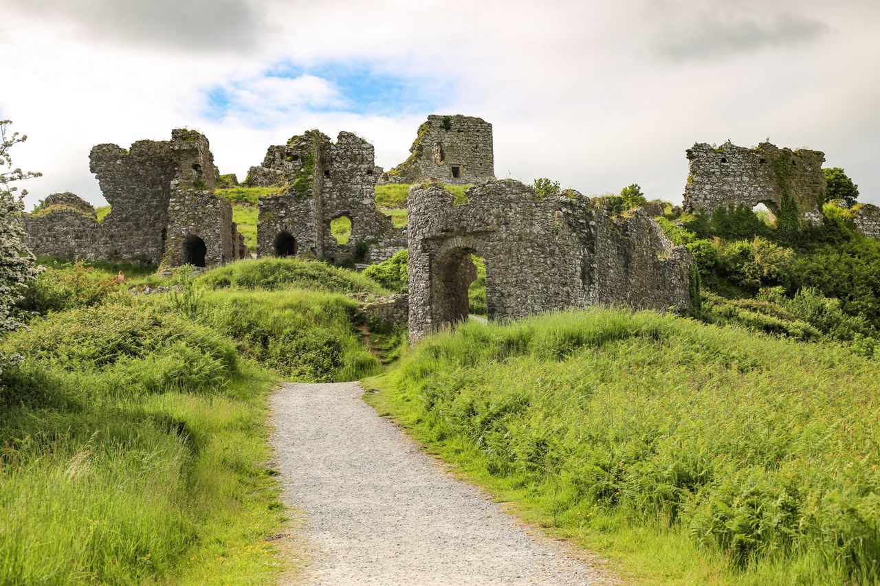 Best eSIM for Northern Ireland; an ancient stone castle in Northern Ireland surrounded by lush greenery under a cloudy sky.