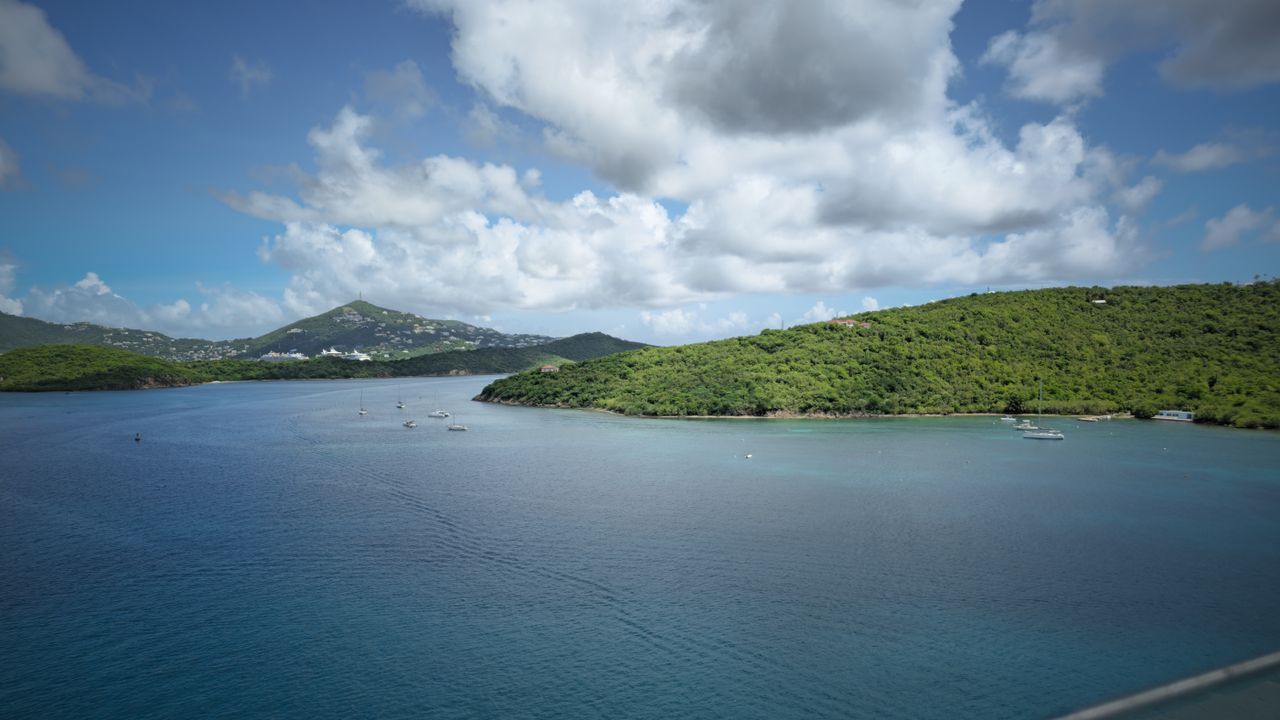 Best Saint Martin eSIM for travel; a view of a tropical bay in Saint Martin with deep blue water, green hillsides, and distant mountains.