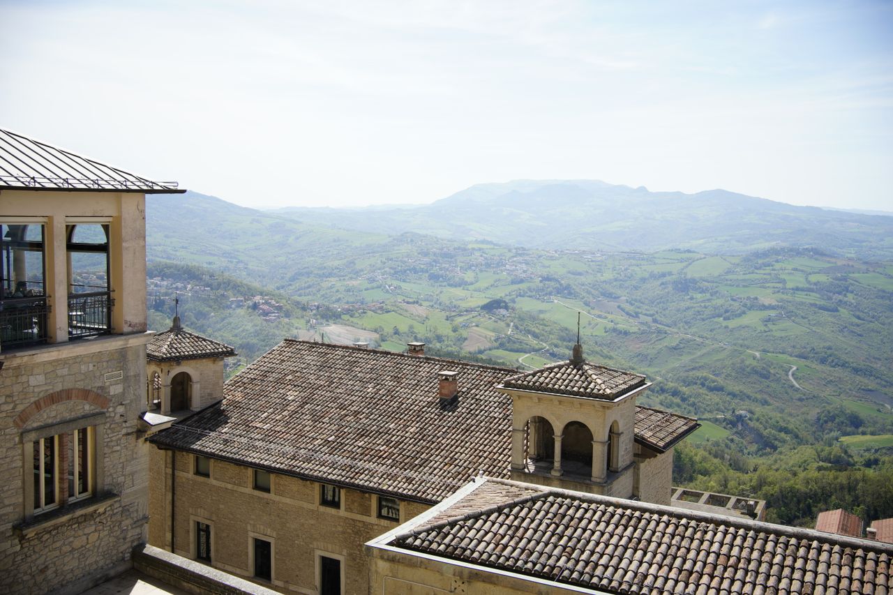 Best eSIM for San Marino; scenic mountain valley with green hills in San Marino, stone buildings in the foreground.