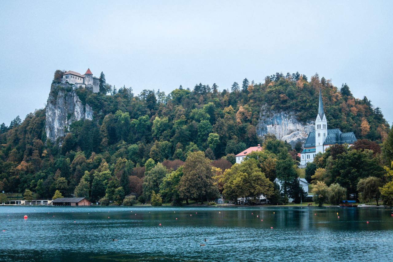 Best eSIM for Slovenia travel - photograph of picturesque lake with town perched on cliffs above the Slovenia lake.