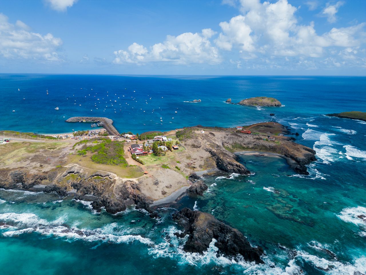 Best eSIM for Saint Barthelemy; aerial view of a rocky coastal island in St Barthelemy surrounded by turquoise ocean water, with white surf.