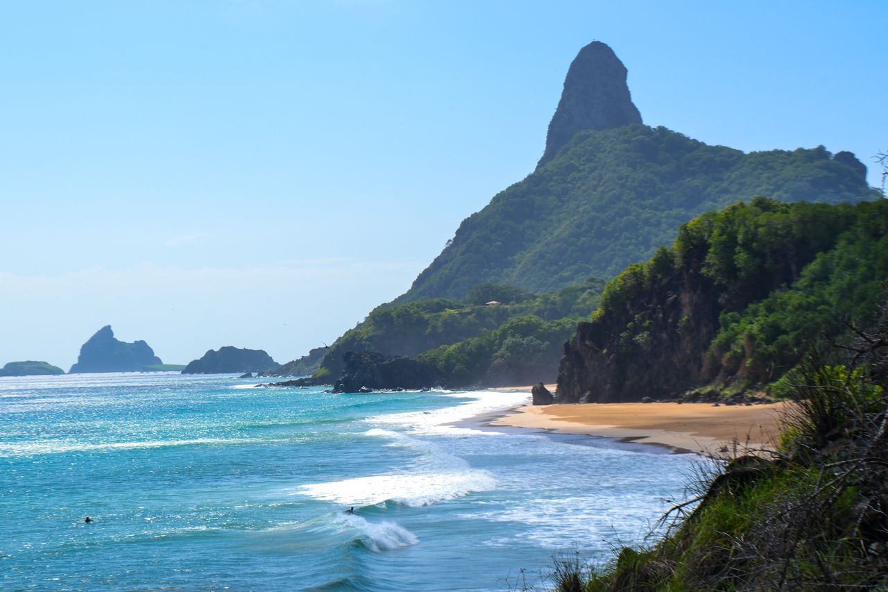 Best eSIM for Saint Lucia travel; a scenic coastal landscape in Saint Lucia with turquoise ocean waves, a sandy beach, lush green cliffs, and a prominent rocky mountain.