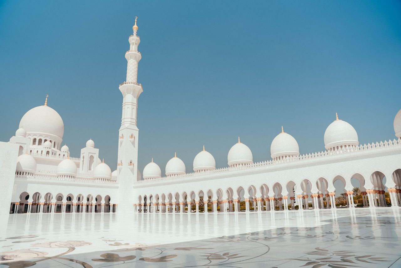 UAE eSIM plans for travel - White mosque in UAE with marble courtyard and marble white towers and domes.