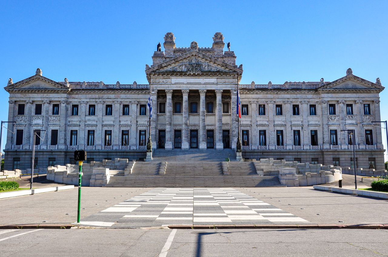 Best Uruguay eSIM for travel; a large neoclassical stone government building in Uruguay with a grand central staircase, columns, and symmetrical wings. 