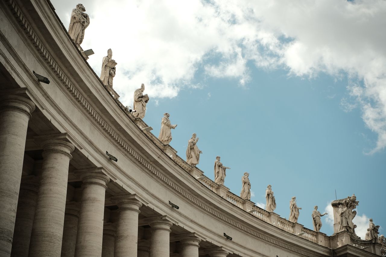 Best eSIM for Vatican City; the curved colonnade of St. Peter's Basilica in Vatican City, featuring numerous stone statues along the roofline.