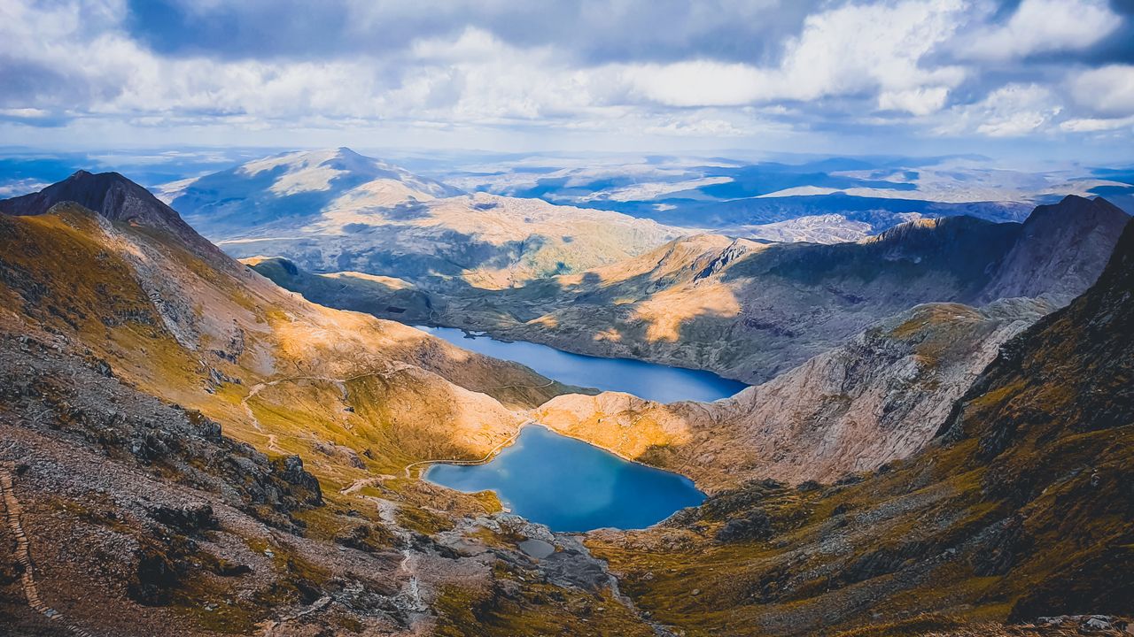 Best Wales eSIM for travel; a mountain landscape in Wales with two blue alpine lakes nestled in a rocky valley, under a cloudy sky.