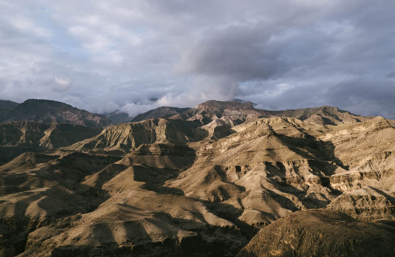 Best Afghanistan eSIM for travel; a dramatic landscape of rugged, sunlit hills and mountains in Afghanistan under a cloudy sky.
